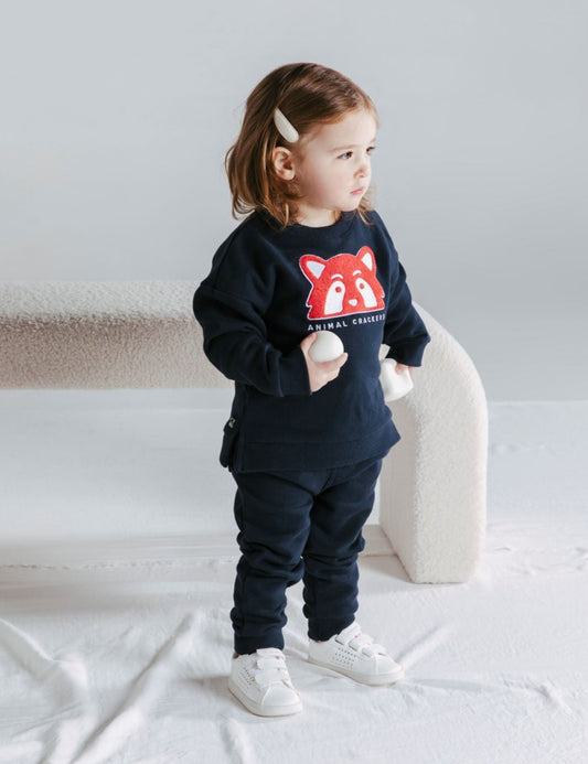 This cute sweatshirt is made from brushed back cotton, just perfect to keep your little one warm! With a relaxed fit and side seam splits you can easily layer up underneath. The left shoulder has left side shoulder domes for ease of dressing. Completing the look is Raffi on the front in red and white which is stunning against the navy. Pair with the Contrast Raffi Pants for a stylish winter look.
